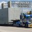 Royal Blue semi truck on the freeway with a yellow oversize load banner attached to the bumper pulling an oversized load on a 5 axle removable gooseneck trailer - Texas Heavy Haul Trucking Company - Equipment Express LLC